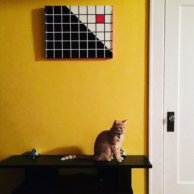 orange cat sitting on furniture under an abstract painting